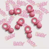 Close-up of pink baby shower scatter confetti pieces and the plastic dummy charm included