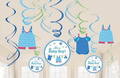 Baby boy shower decoration set featuring blue and green hanging swirl ribbons, baby clothes cutouts, and circular 'it's a Baby Boy!' signs, shown against a light room background with a Party World logo at the bottom.