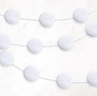 White honeycomb ball garland two metres long strung across a wedding reception wall