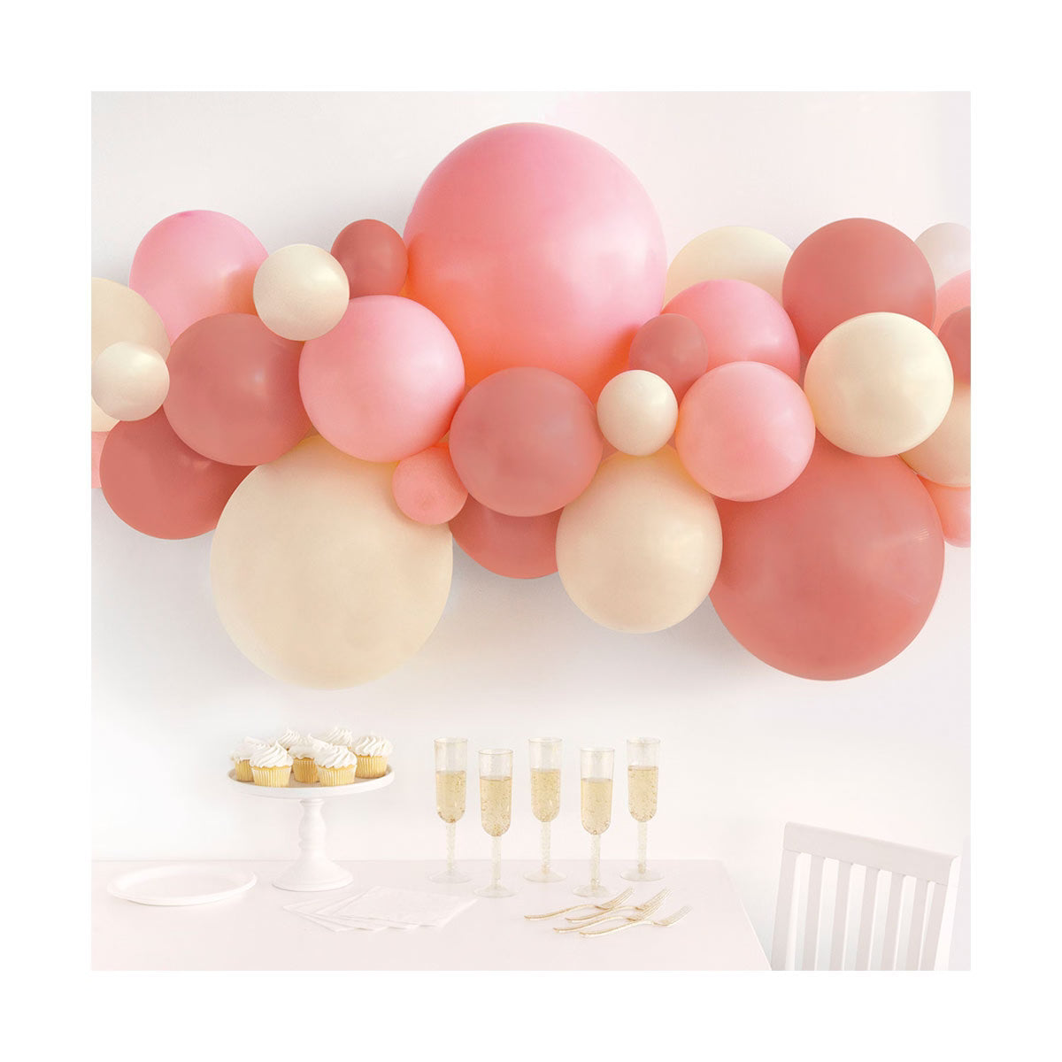 Balloon arch with pink, white, and red balloons above a table set for a celebration.